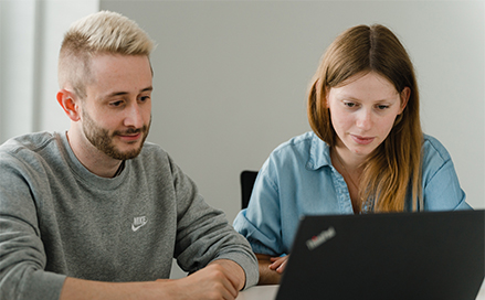 junge Frau und Mann schauen auf Laptop